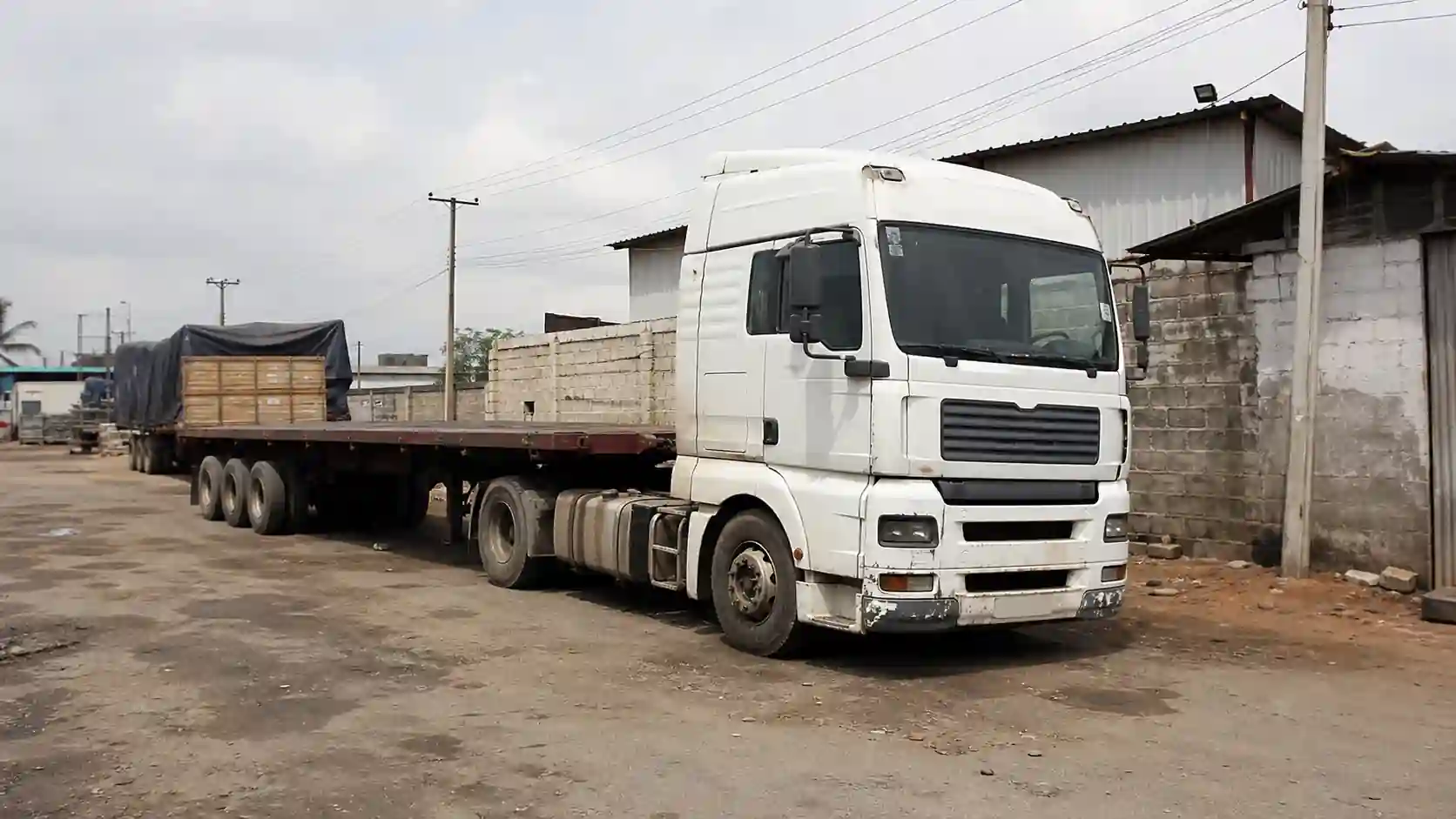 Flatbed semi-trailer carrying cargo on an African yard route